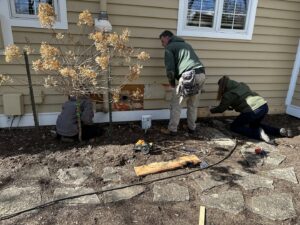 A crew repairing the base of a house's siding with tools on the ground by Cedar Siding Repair in Centerville, OH.