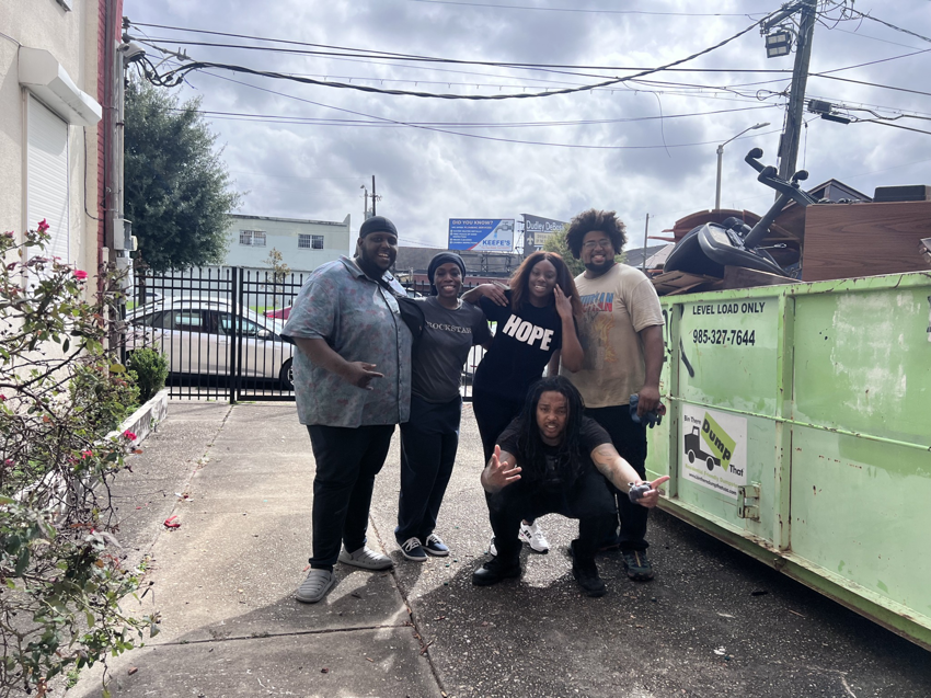 A crew standing next to a large dumpster filled with junk for Weekly Waste Solutions in Jackson, MS.