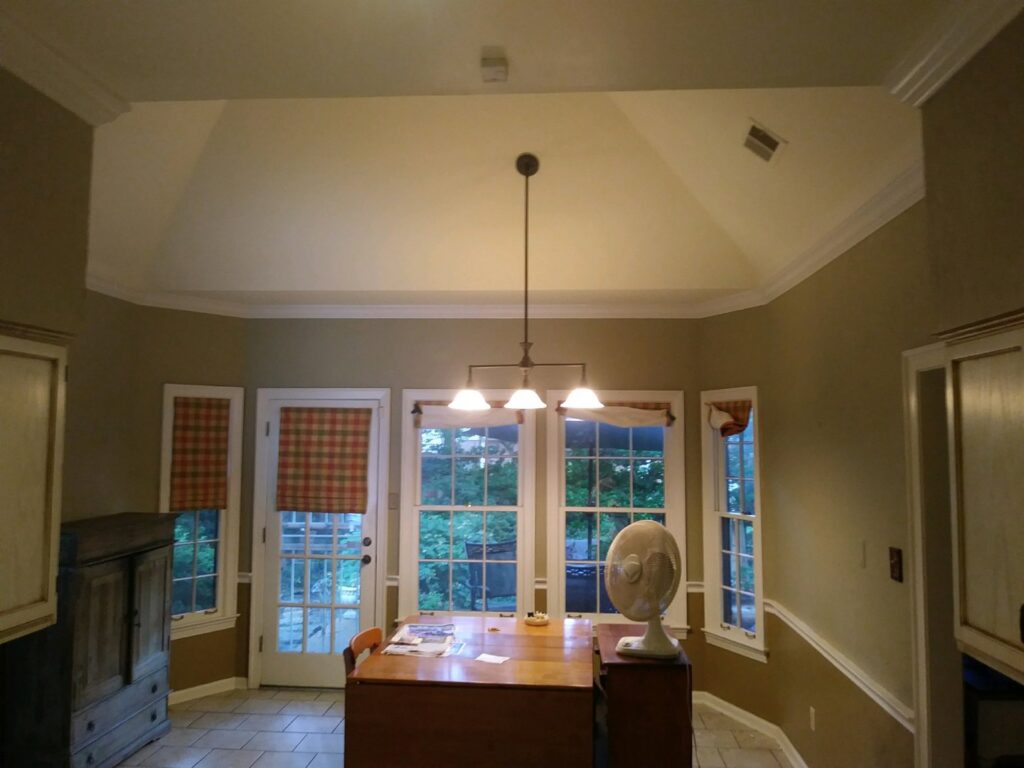 A dining area with elegant crown molding and a new light fixture installed by Custom Carpentry Service in Knoxville, TN.