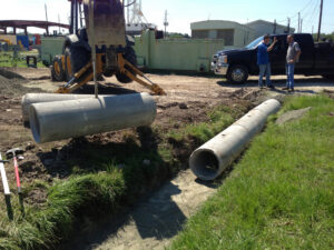 Heavy equipment lifting concrete culvert pipes for installation by Daniel Dean Land Clearing & Dirt Work in Houston, TX.