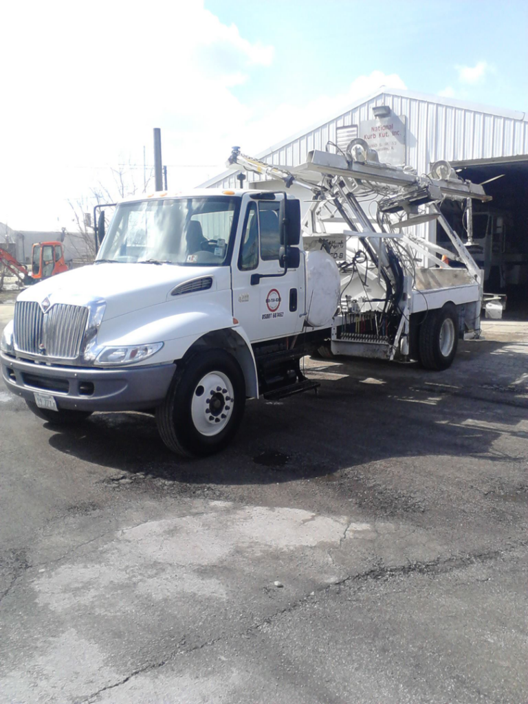 A specialized curb machine truck parked at National Kurb Kut in Naperville, IL, ready for general contractor work.