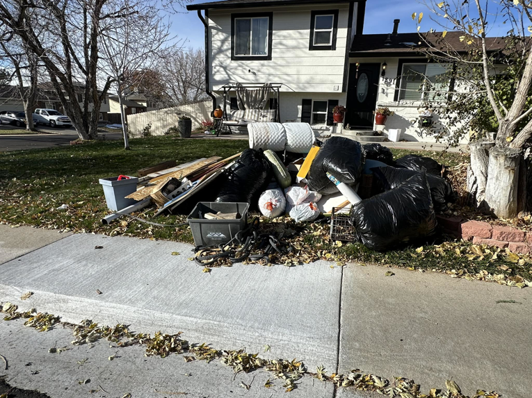 A large pile of household junk and trash bags placed curbside for pickup by Denver Dumpsters in Denver, CO.