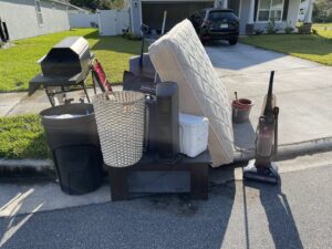 Large household items like a mattress, grill, and furniture piled curbside for junk removal by Junk Removal JAX in Jacksonville, FL.