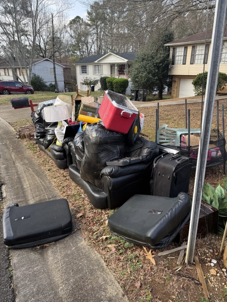 A large curbside pile of furniture, trash bags, and various junk items awaiting removal by LP Junk Removal in Birmingham, AL.