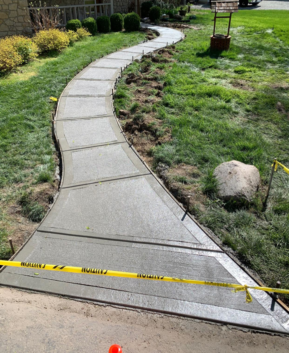 A long, curved concrete pathway installation in progress, completed by Complete Concrete of Indy, Inc. in Fishers, IN.