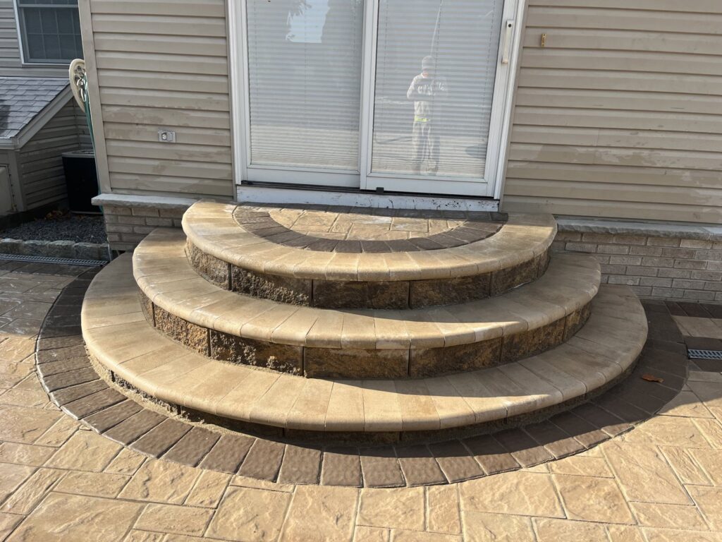 Newly installed curved paver steps and patio leading to a sliding glass door by Mincho Contractor LLC in Jersey City, NJ