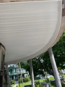 Newly installed white soffit and ceiling on a curved porch, showcasing finish work by Usa Construction of Danbury LLC in Danbury, CT.
