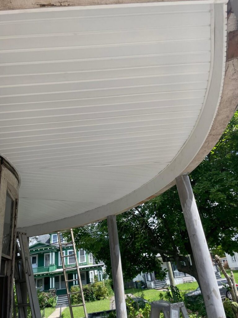 Newly installed white soffit and ceiling on a curved porch, showcasing finish work by Usa Construction of Danbury LLC in Danbury, CT.