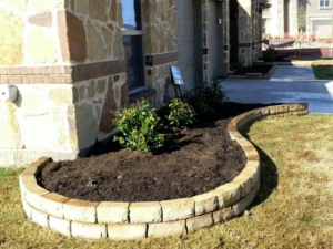 A curved stone planter bed or retaining wall built alongside a home by Contractors Stone Supply in Plano, TX
