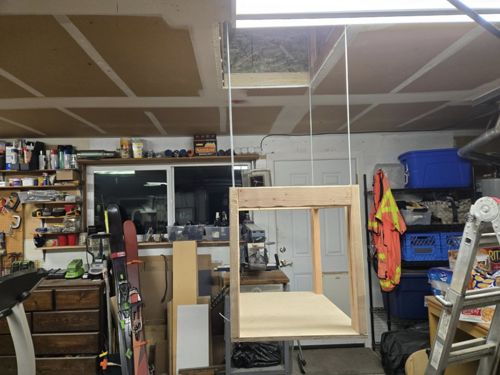 A custom-built attic lift platform being operated in a garage by Hands On Repair in Renton, WA.