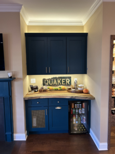 A custom-built home bar area featuring dark blue cabinets and a wooden countertop, installed by Safe Haven Home Services in Nashville, TN.