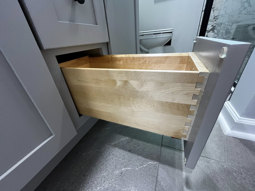 An open custom wooden drawer in a newly installed bathroom vanity by Simko Tile & Bath, showcasing quality in Macon, GA.