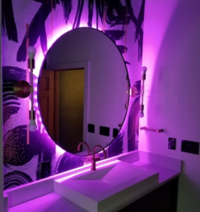 A custom bathroom vanity with a unique sink and a round LED-backlit mirror, installed by Longhouse Construction Inc. in Estacada, OR.