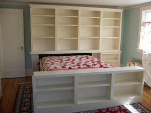 Custom bedroom built-in shelving and cabinet unit around a bed by Hessel Carpentry in Portland, OR.