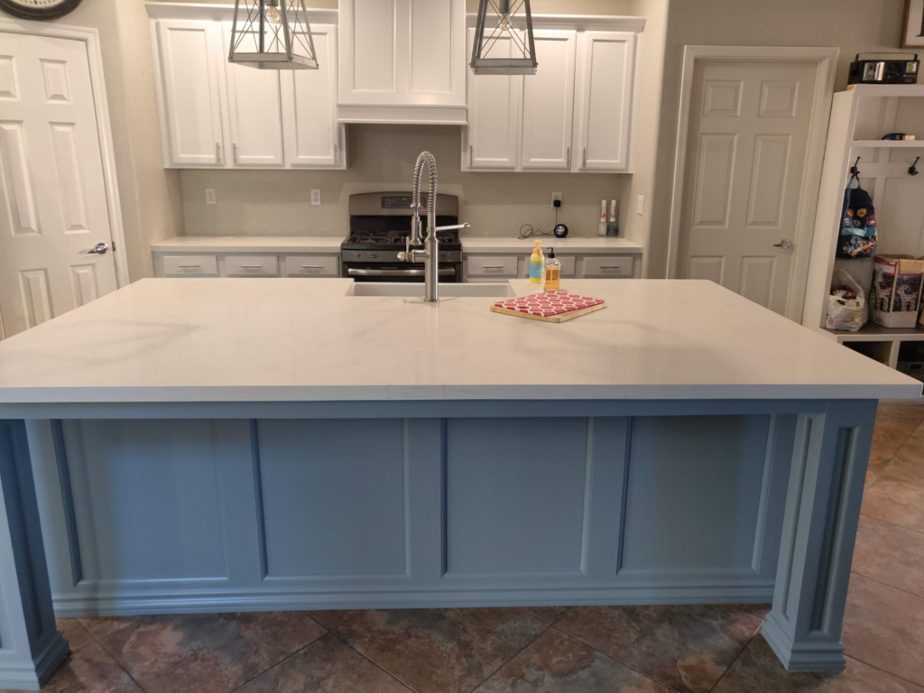 A close-up of a custom blue kitchen island with built-in shelving by Camelback Cabinets in Gilbert, AZ