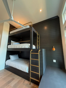 A custom-built triple bunk bed with brass ladders, expertly installed by Kerley Construction INC. in Greenville, SC.