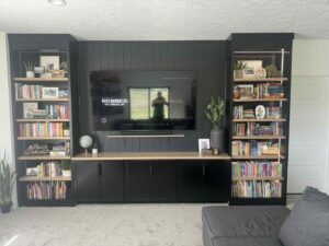 A custom-built entertainment center with shelving and a wall-mounted TV by Renegade Woodworks in Kearney, NE.
