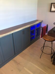 Custom built-in cabinets with a live-edge wooden countertop and accent lighting by The Huckleberry Handyman in Meridian, ID.