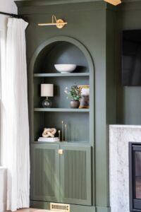 A custom-built green shelving unit next to a fireplace, expertly crafted by Westrick Homes in St. Louis, MO.
