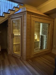 A custom-built wooden sauna structure installed neatly under a staircase by Upstate Modern Builders LLC in Greenville, SC.