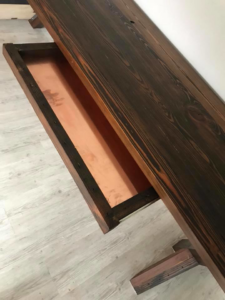A custom-built dark wooden table featuring a unique copper-lined hidden drawer, crafted by Aggregate in Enid, OK
