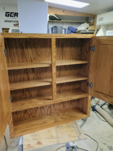 Interior view of a custom-built wooden cabinet with adjustable shelves by The Cowboy Carpenter Handyman Service LLC in Bismarck, ND.