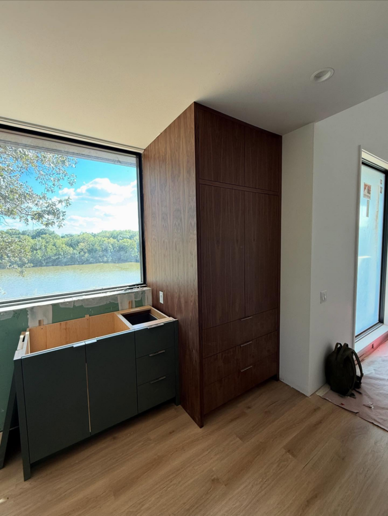 Custom wooden and green base cabinets installed in a room under construction by Red Beard Cabinets in Kansas City, MO.