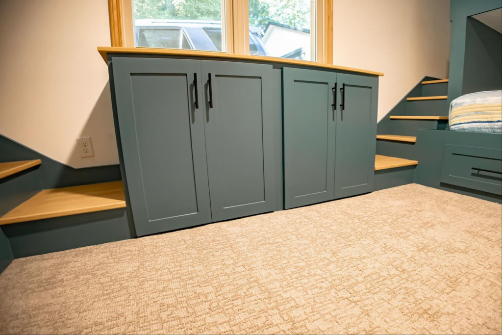 Close-up of custom built-in cabinets and stairs under a window, a carpentry job by An Extra Hand in Indianapolis, IN.