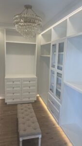 A custom closet with built-in shelving, drawers, and a chandelier installed by Four Seasons Building & Remodeling in Mauldin, SC.