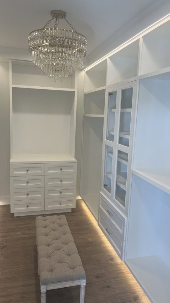 A custom closet with built-in shelving, drawers, and a chandelier installed by Four Seasons Building & Remodeling in Mauldin, SC.
