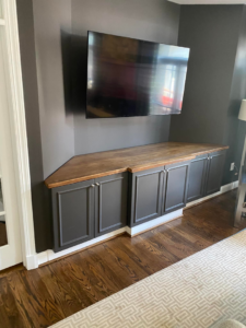 Custom built-in corner cabinets with a wooden countertop and wall-mounted TV by Andyman,LLC in Fredrick, MD.