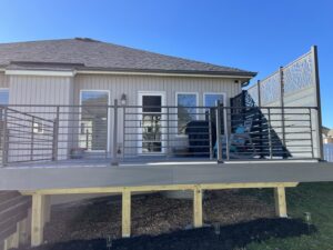 A custom deck design featuring modern railings and a decorative screen by Chad Fry the Deck Guy LLC in Blue Springs, MO.