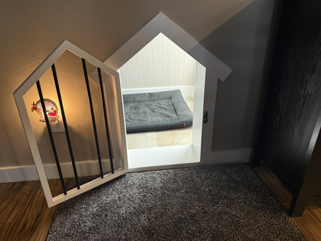 A custom-built dog nook under a staircase with an open decorative gate by JJ's Handyman Service in Las Vegas, NV