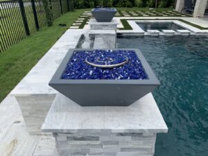 Custom fire bowls and water features adorning a poolside area, expertly crafted by Limitless Custom Pools and Backyards in Houston, TX.