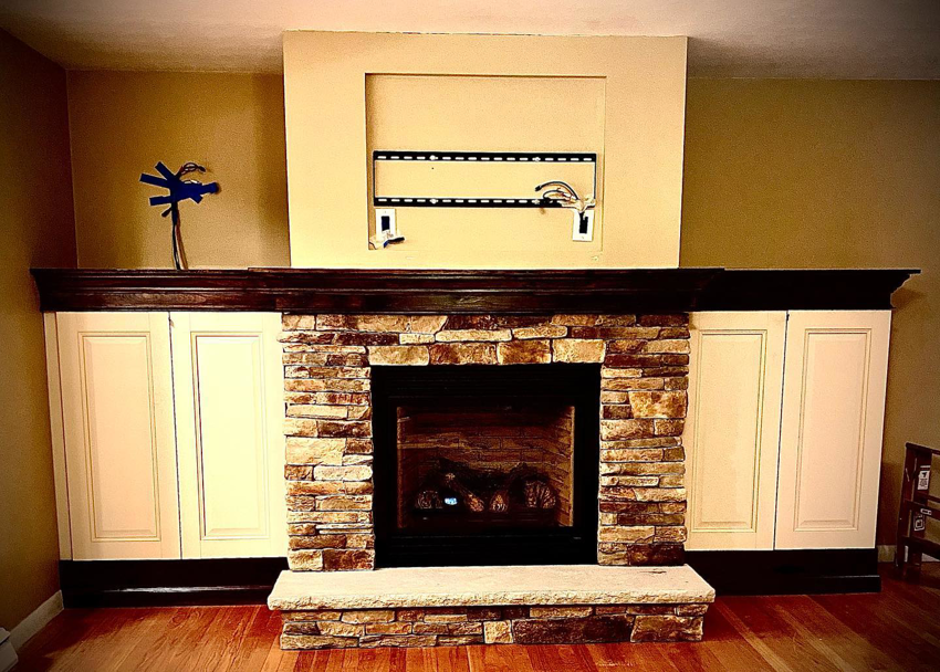 A custom stone fireplace with built-in cabinets and TV mount area by Mohawk Home Improvement of Syracuse LLC in Syracuse, NY.