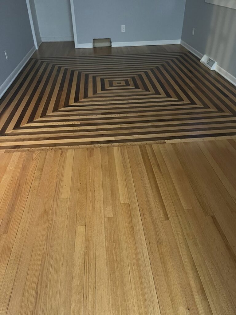 A unique geometric pattern hardwood floor design installed by Nelson Hardwood Flooring in Madison, WI, transitioning to standard planks.
