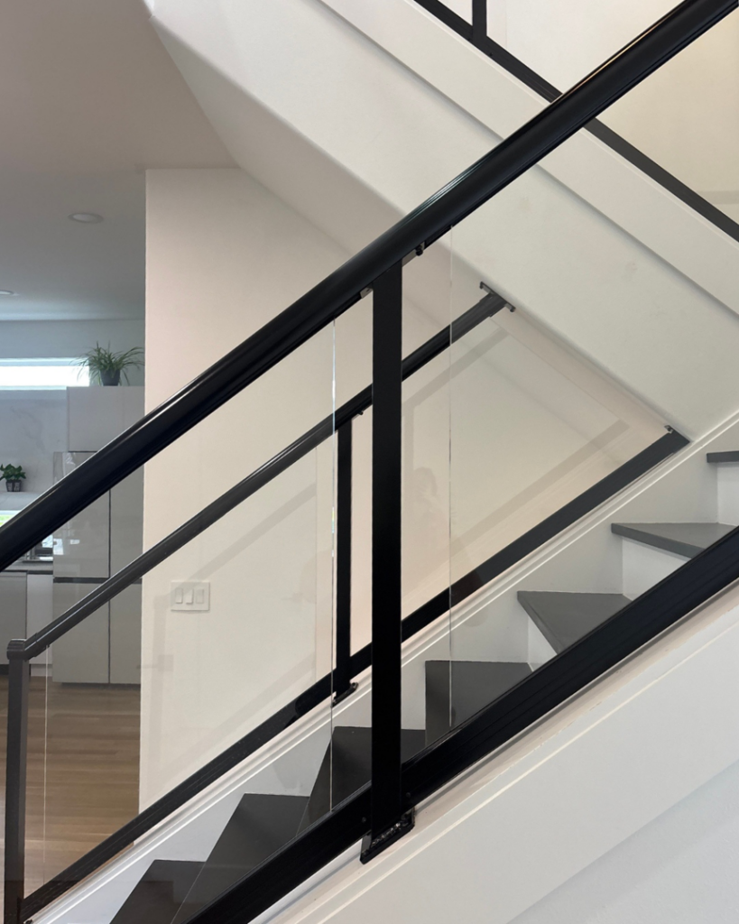 Close-up view of custom black framed glass railings on a modern staircase by Alpha Railing Company in Tacoma, WA.