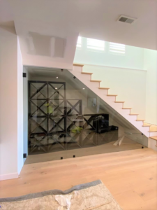 Custom glass wine rack installation under a staircase by Thermal Concepts, Inc in St. Louis, MO.