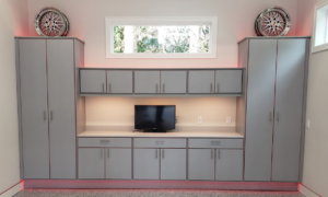 Custom grey garage cabinets with a workbench, TV, and under-cabinet lighting installed by NW Garage Cabinet Company in Ridgefield, WA.