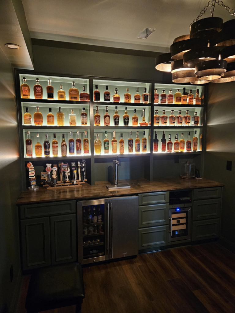 A custom home bar installation with illuminated shelves and beer taps by Antalek Construction LLC in Erie, PA