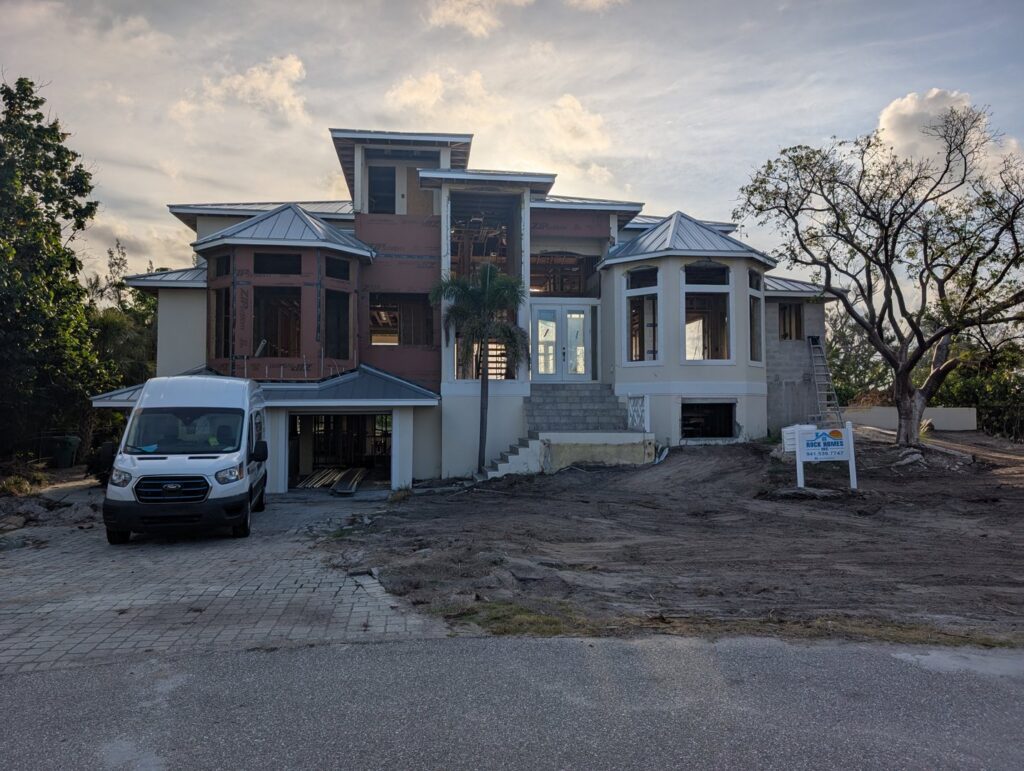 Front view of a custom home under construction with a work van and 'Rock Homes' sign by Rock's Custom Homes in St. Petersburg, FL.