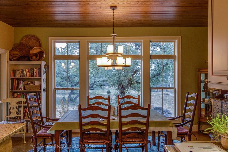 A custom home dining room with a large window and elegant chandelier by Aubrey Homes in Austin, TX