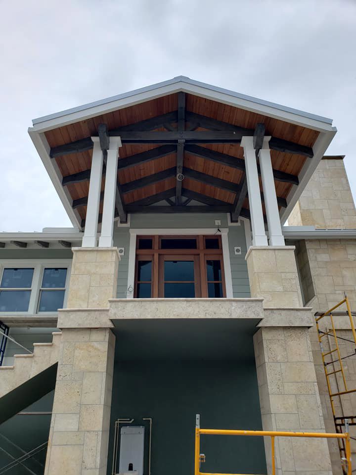 The entrance of a custom home under construction with exposed wood ceiling and scaffolding by Rock's Custom Homes in St. Petersburg, FL.