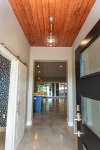 A custom home entryway featuring a wooden plank ceiling and modern light fixture by Aubrey Homes in Austin, TX