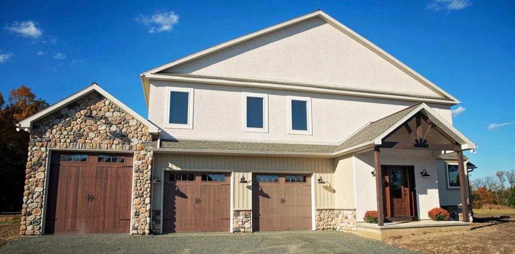 Exterior of a custom home featuring stucco, stone siding, and multiple garage doors by Corrado Custom Homes, Inc. in Kutztown, PA