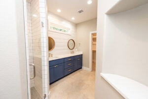A custom home master bathroom with a double vanity, blue cabinets, and walk-in shower by Aubrey Homes in Austin, TX