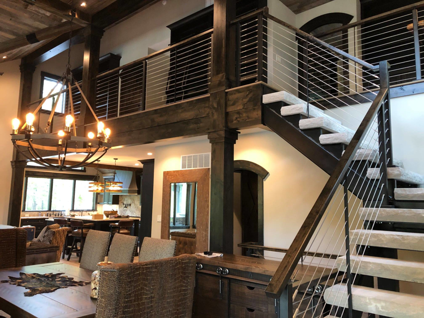 A custom interior featuring a wooden staircase, modern railings, and exposed beams by Grabill Painting and Drywall in Fort Wayne, IN.