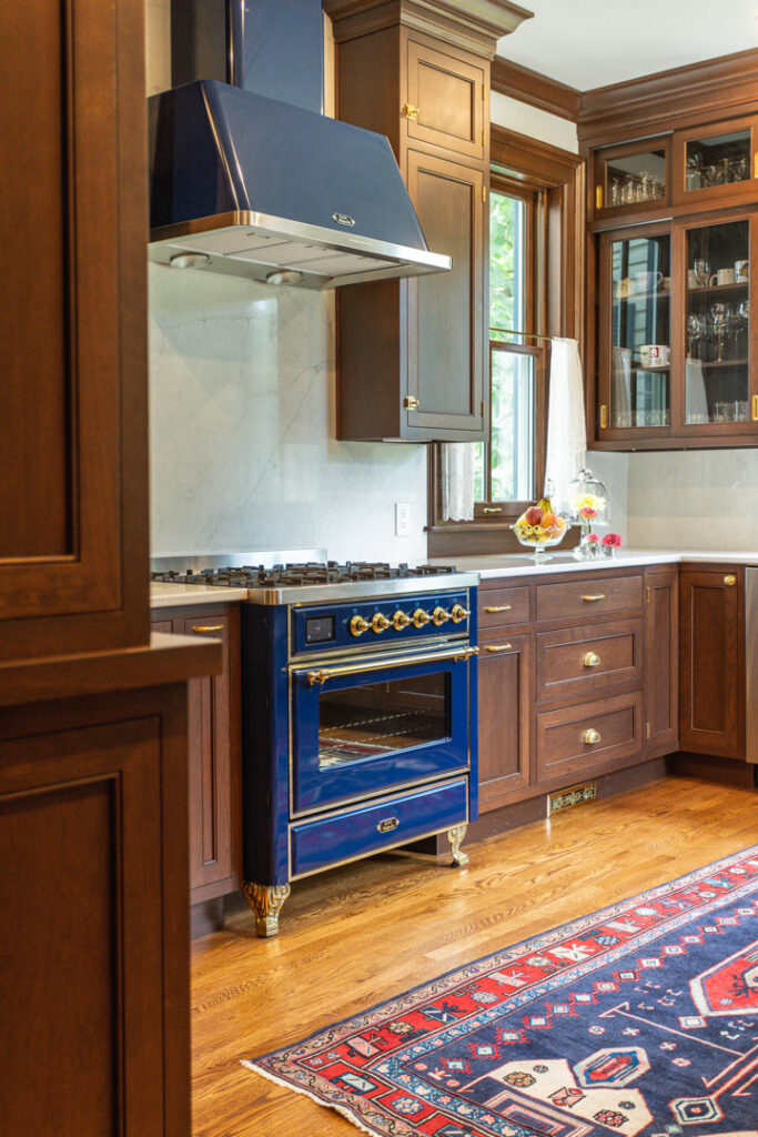 A custom kitchen featuring a striking blue professional range, matching hood, and elegant dark wood cabinets by Legacy Builders Group in Cincinnati, OH.