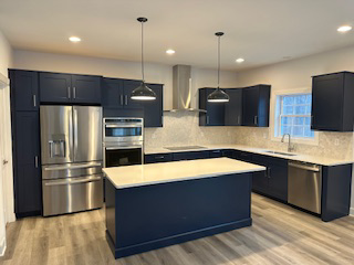 A custom kitchen design with dark blue cabinets, a matching island, and stainless steel appliances by McDonald Custom Homes in Schenectady, NY.
