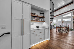 A custom kitchen pantry and coffee bar area with white cabinetry and a spiral staircase in the background, built by Bob Build's WNY in Buffalo, NY.